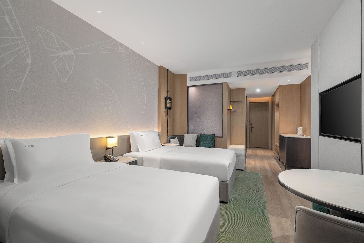 Una habitación de hotel con dos camas, un escritorio, un televisor y un baño.
