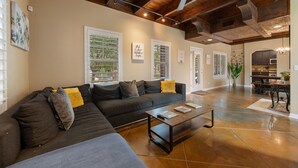 A modern living room with a sectional sofa, a coffee table, and a ceiling fan. - ATX Oasis!  3-Story Home w/ Heated Pool, Spa & Sauna - Close to downtown (Austin)