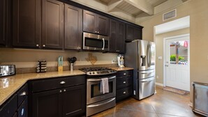 A modern kitchen with dark cabinets, stainless steel appliances, and a granite countertop. - ATX Oasis!  3-Story Home w/ Heated Pool, Spa & Sauna - Close to downtown (Austin)