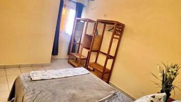 Ein Schlafzimmer mit einem Bett, einem Holzschrank, einem kleinen Tisch und einer Topfpflanze.