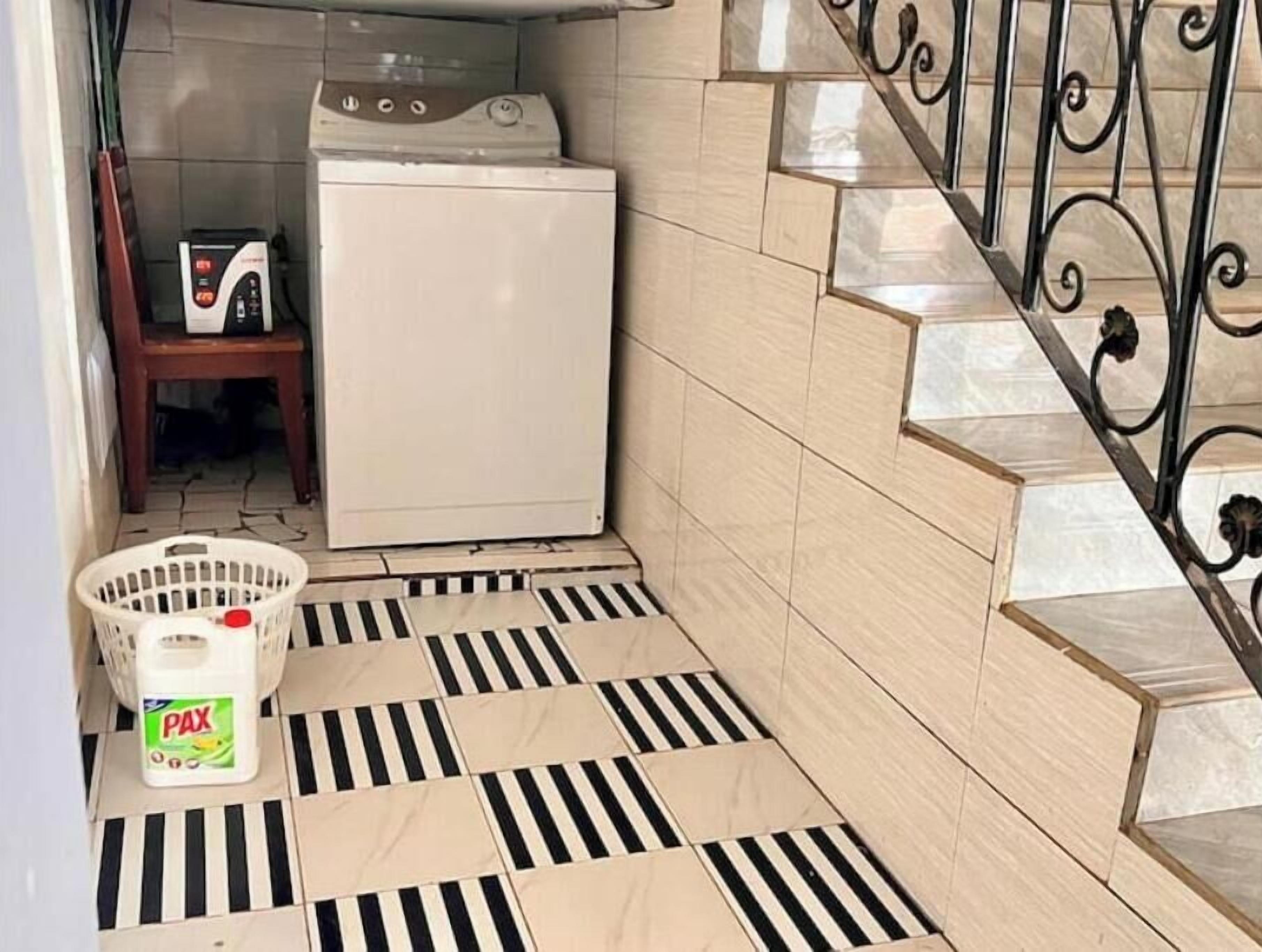 Een wasruimte met een wasmachine, een droger, een wasmand en een fles wasmiddel.