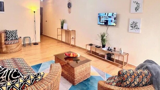 A living room with a sofa, a coffee table, a TV, and a plant. - Residence Ethan Nji - Amazing loft (Yaoundé)