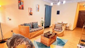 A living room with a sofa, armchair, coffee table, and a rug. - Residence Ethan Nji - Amazing loft (Yaoundé)