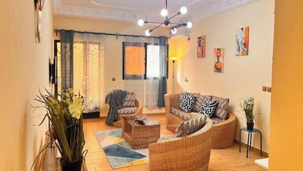 Una sala de estar con muebles de mimbre, un ventilador de techo y obras de arte en las paredes.