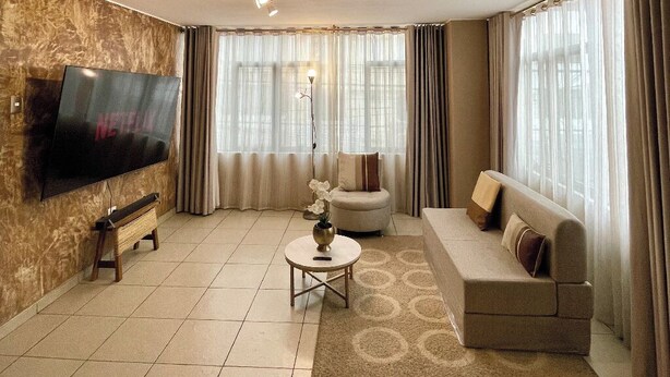 A living room with a flat-screen TV, a sofa, a round coffee table, and a patterned rug. - Luxury Apartment: 3BR\2BA\6G Work, Studio & Family - Live Like a Local Peruvian (Lima)