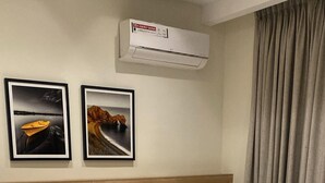 A neatly made bed with white and gray bedding, two framed pictures on the wall, and a gray curtain. - Adar Hotel (Lagos)