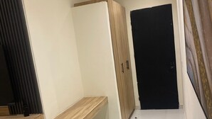 A hallway with a wooden bench, a wardrobe, and a black door. - Adar Hotel (Lagos)