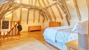 A rustic bedroom with exposed wooden beams, a wooden bed, a bedside table, and a radiator. - Charmante Maison avec piscine (Journiac)