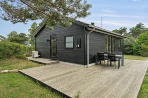 A small cabin with a deck, a table and chairs, and a door.