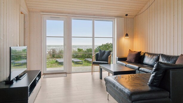 A modern living room with a TV, leather sofa, and a table. - Holiday home by Balka Beach with perfect location (Nexø)
