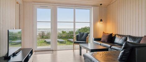 A modern living room with a TV, leather sofa, and a table.