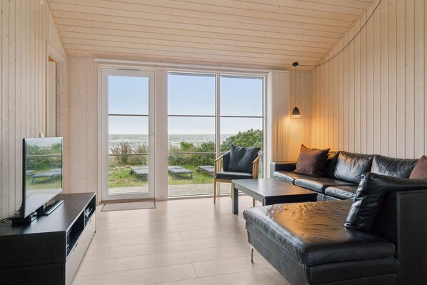 A modern living room with a TV, leather sofa, and a table.