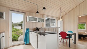 A modern kitchen with a central island, built-in cabinets, and a dining area with a table and chairs. - Holiday home by Balka Beach with perfect location (Nexø)