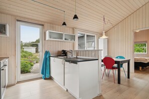A modern kitchen with a central island, built-in cabinets, and a dining area with a table and chairs.