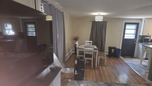 A compact kitchen with a marble countertop, a dining area with a table and chairs, and a black door with a window. - Charming 3-bedroom house in delightful Peabody (Peabody)