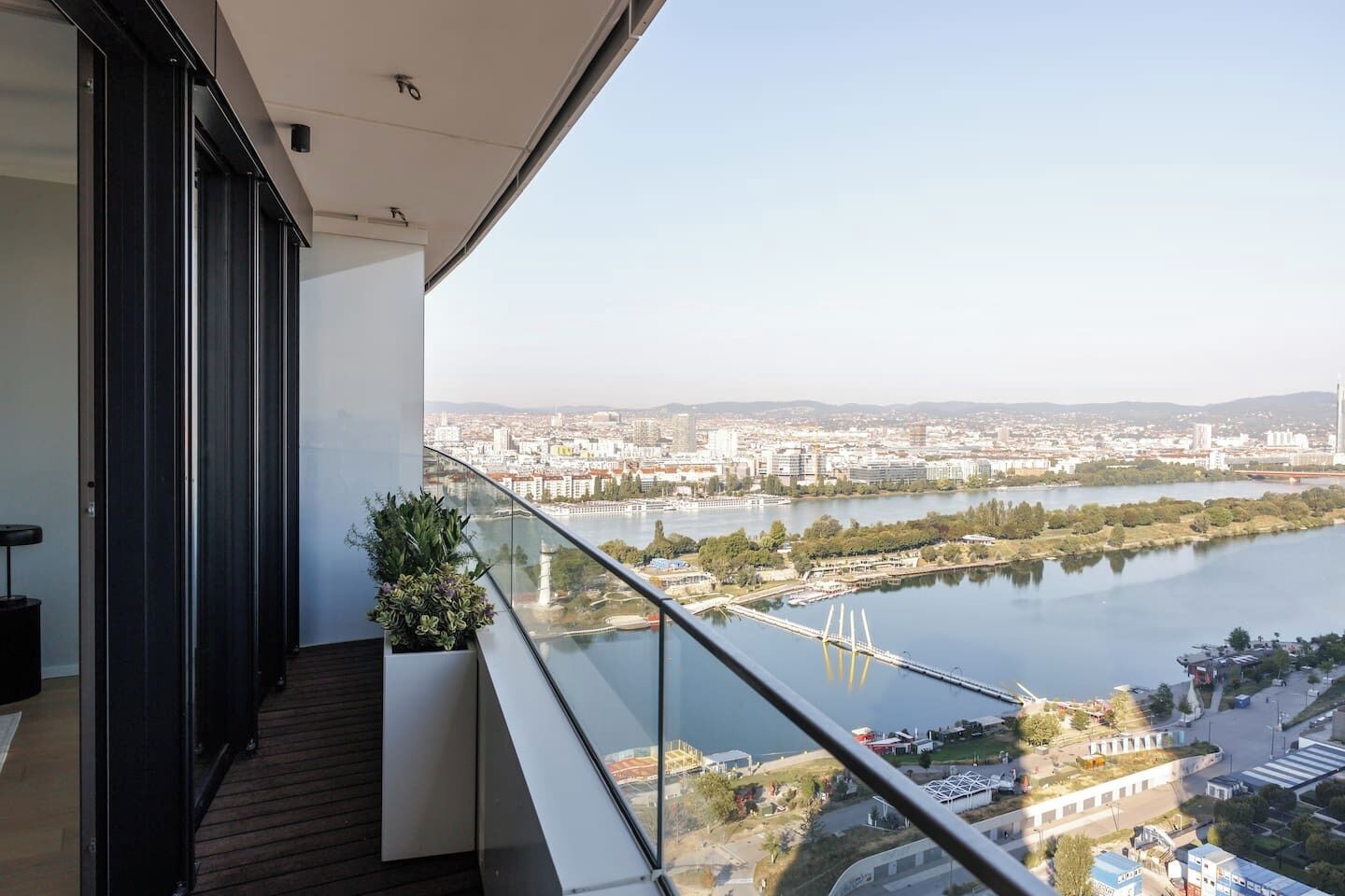 Ein Balkon mit Blick auf einen Fluss und eine Stadtlandschaft, darunter eine Brücke und Gebäude.