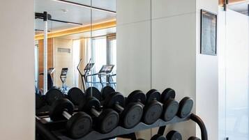 Ein Fitnessstudio mit Hantelbank, Laufband und Spiegelwand.