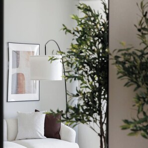 A modern bedroom with a bed, a wall-mounted lamp, and a framed abstract artwork.
