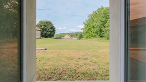 A view through a window of a grassy yard with a building and trees. - 2 bedroom amazing home in Monthenault (Monthenault)