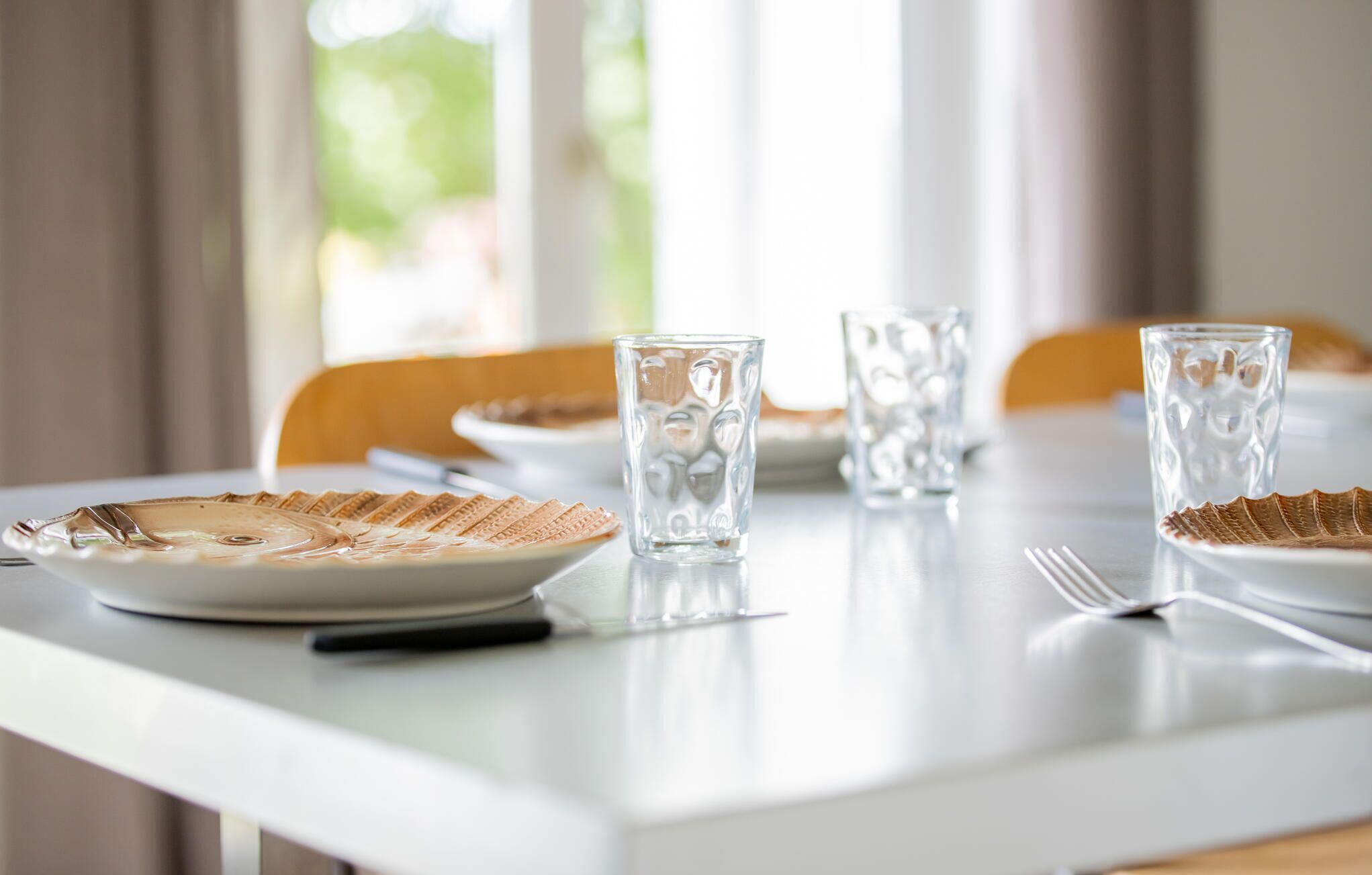 Una mesa de comedor dispuesta con platos de gofres, vasos transparentes y cubiertos.