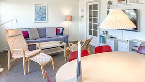 A modern living room with a sofa, chairs, a dining table, a lamp, and a TV. - Lovely apartment in Rudkøbing with house sea view (Rudkøbing)