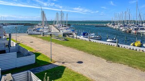 A marina with boats docked, a grassy area, and a pier extending into the water. - Lovely apartment in Rudkøbing with house sea view (Rudkøbing)