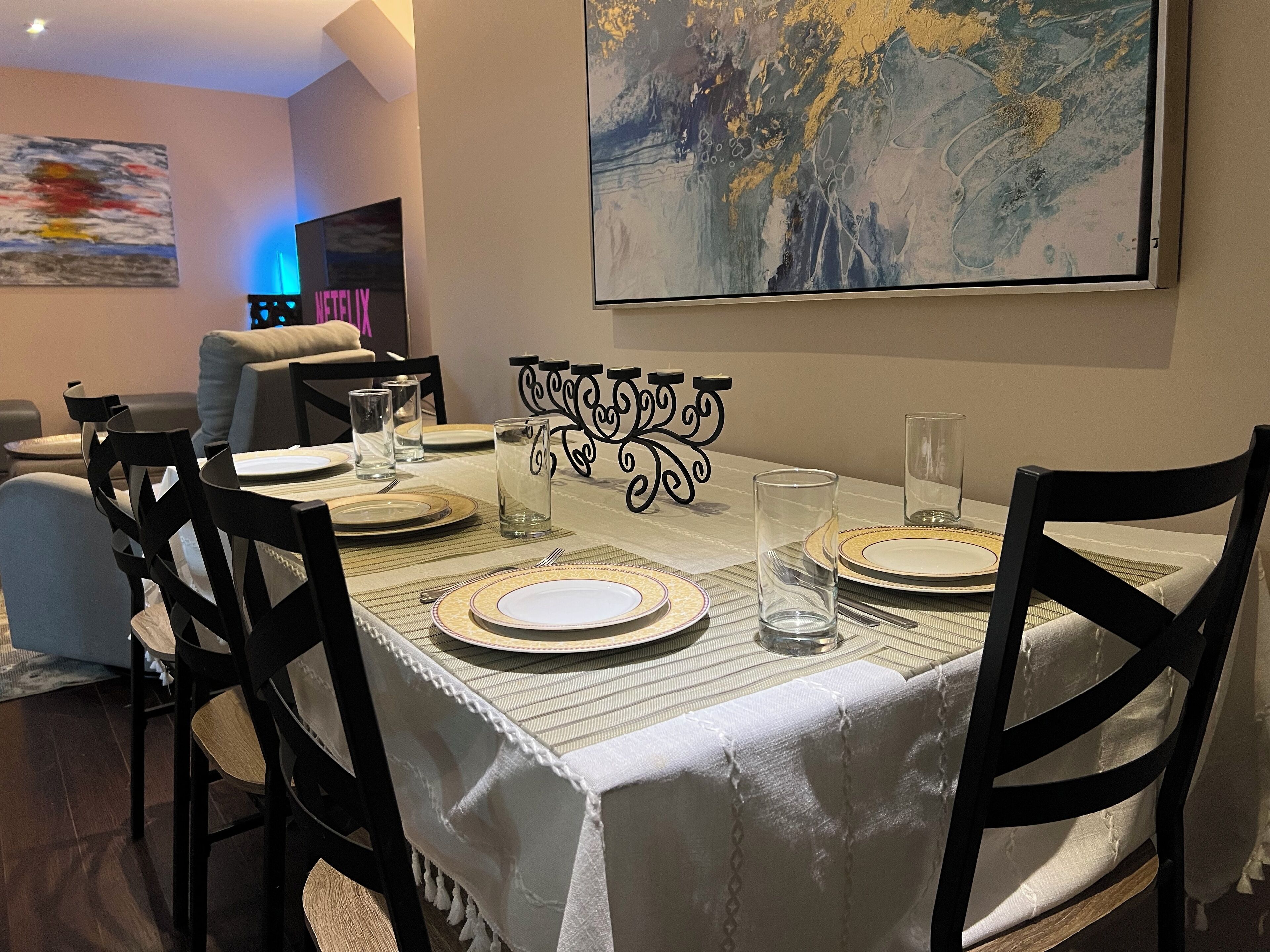 Een eetruimte met een tafel voor vier personen, stoelen en een decoratief metalen middelpunt.
