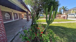 A residential building with a brick facade, a covered porch, and a cactus in the front yard. - Excellent 2-bedroom house near Rosarito Beach (Rosarito)