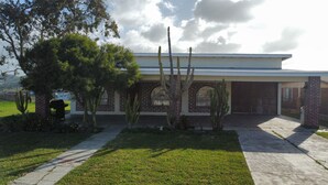 A house with a brick facade, arched windows, and a front yard with cacti and a tree. - Excellent 2-bedroom house near Rosarito Beach (Rosarito)
