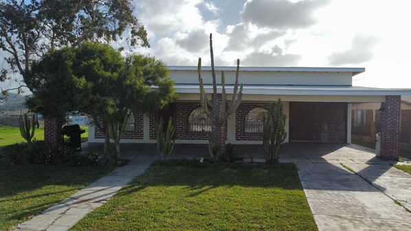 Una casa con fachada de ladrillo, ventanas de arco y un jardín delantero con cactus y un árbol.