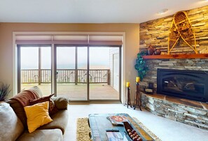 A living room with a sofa, a coffee table, a fireplace, and a balcony with a view. - Reserve 13C • Sugar Mtn. Getaway with Big Views (Sugar Mountain)