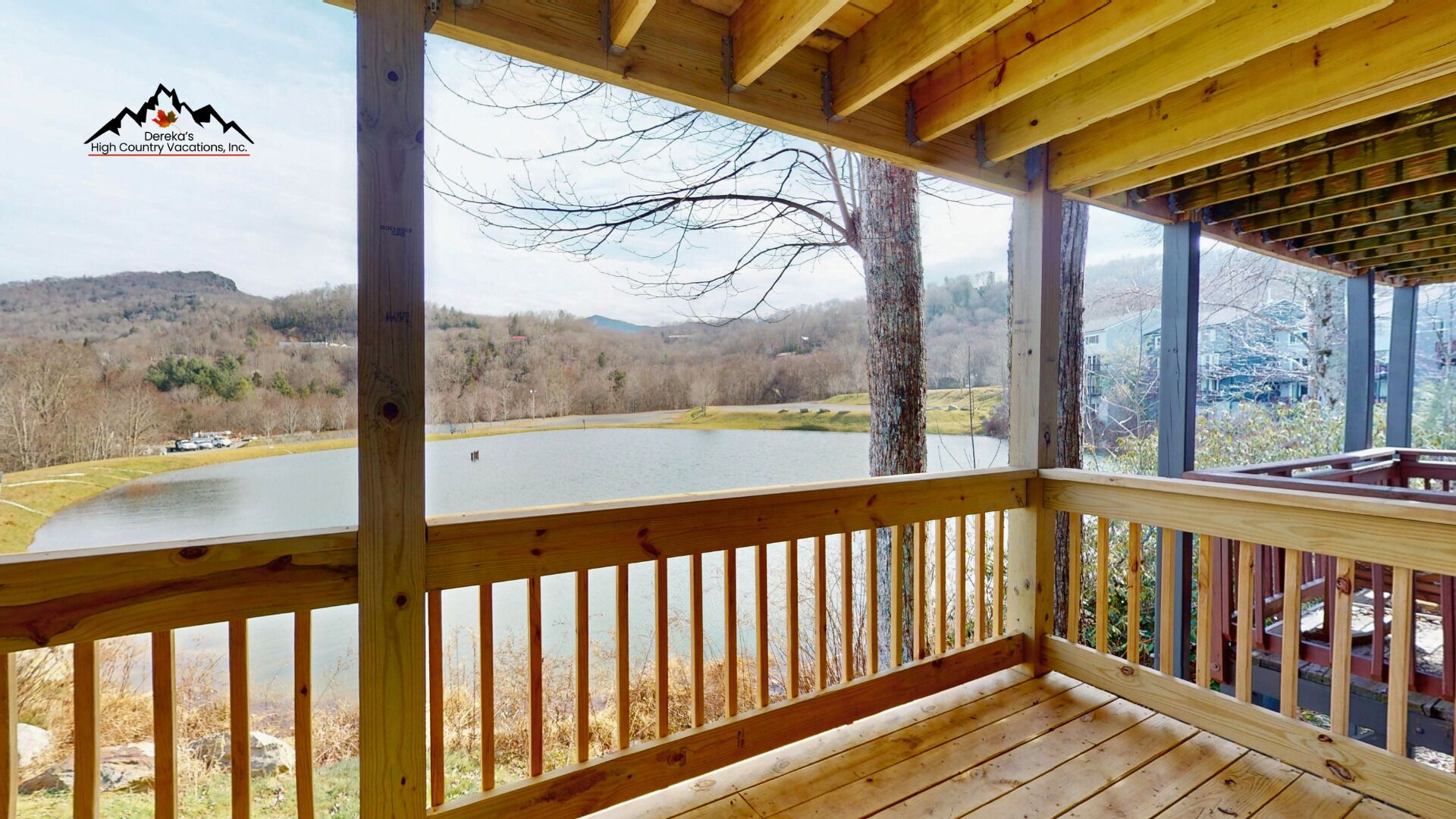 A wooden deck with a view of a lake and mountains.