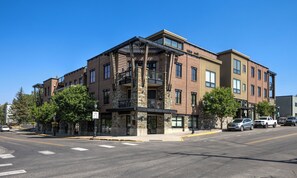 Un immeuble à plusieurs étages, doté d’une façade en pierre, de nombreux balcons et d’un panneau indiquant la présence d’une piste cyclable.