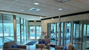 A lobby with three sofas, a coffee table, and a glass door entrance.