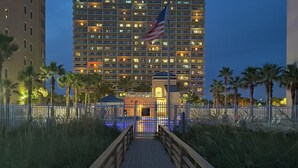 A hotel entrance with a wooden walkway leading to a building with multiple floors and balconies.