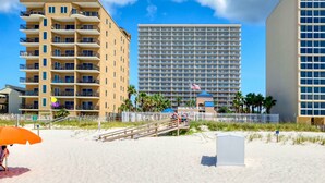 A beachfront hotel with multiple balconies, a beach access walkway, and a clear view of the ocean.