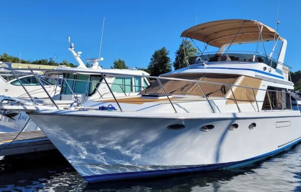 A white yacht with a covered upper deck, multiple windows, and a name "JOSE" on the side. - 2 Cabin Classic Yacht in Petoskey's Bay Harbor (Petoskey)