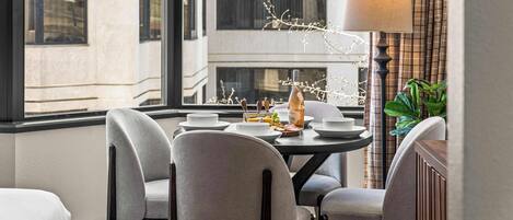 A dining area with a round table, four chairs, and a lamp.