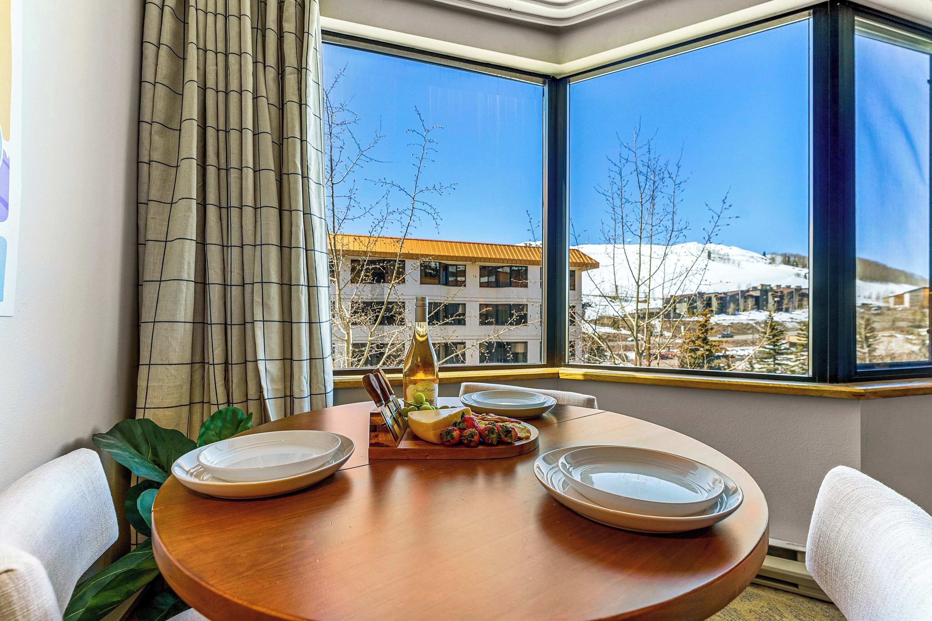 A dining area with a table set for two, a bottle of wine, and a plate of food.