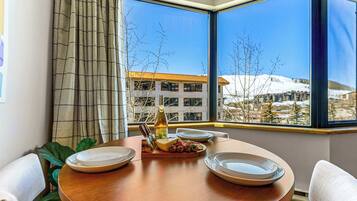 A dining area with a table set for two, a bottle of wine, and a plate of food.