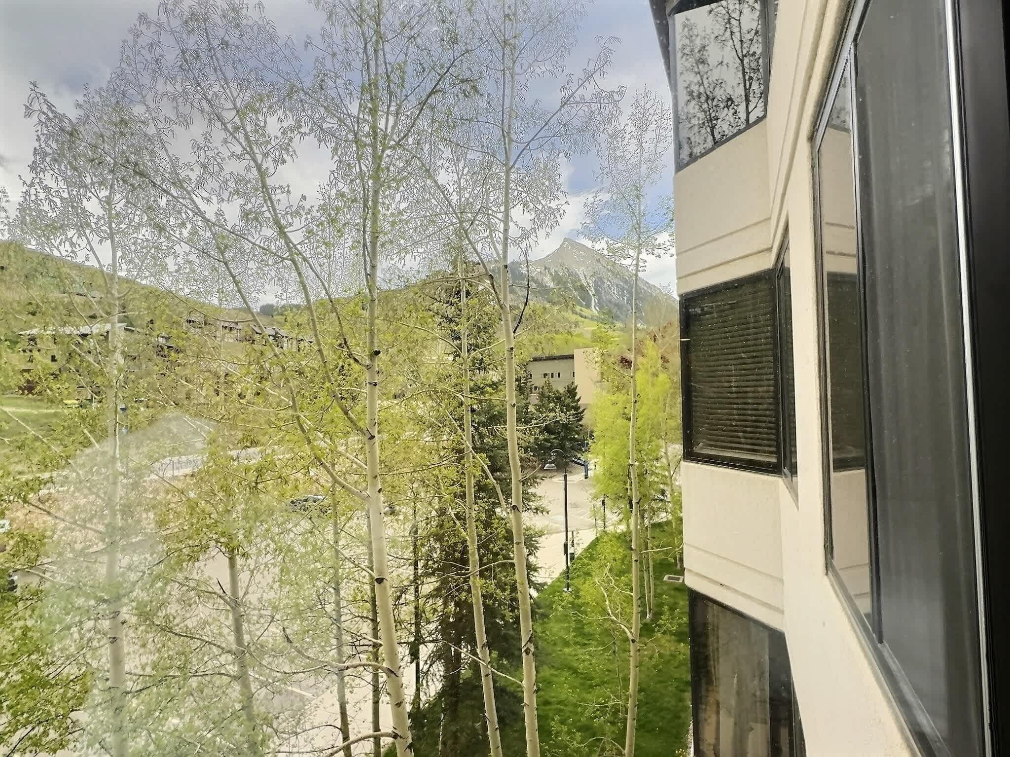 A view from a window overlooking a mountainous landscape with trees and buildings.