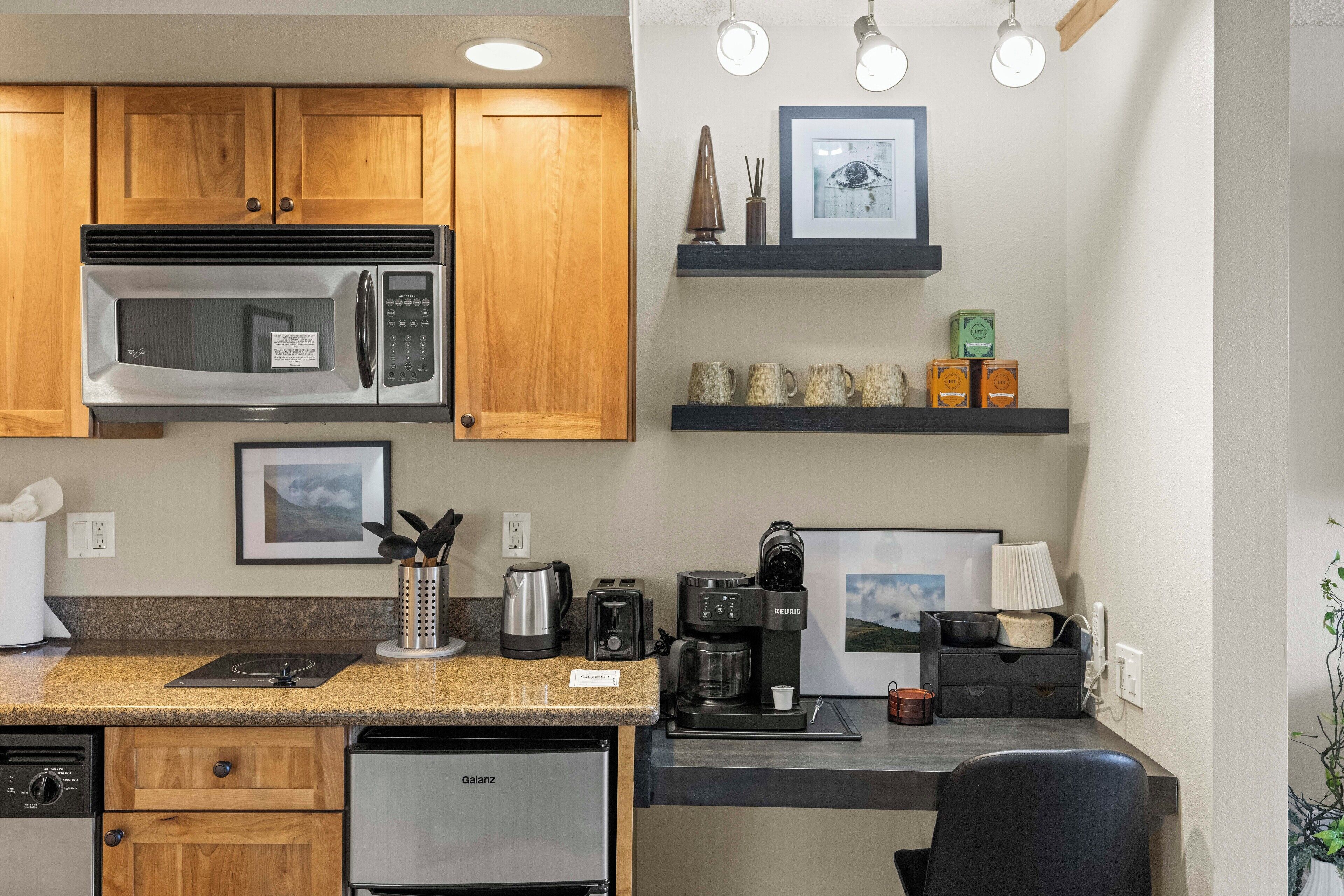A compact kitchen with wooden cabinets, a built-in microwave, a coffee maker, and a dishwasher.