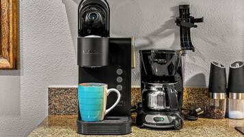 A coffee maker with a blue mug on a granite countertop.