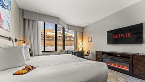 Une chambre d’hôtel moderne dotée d’un grand lit, d’une cheminée, d’une télévision et offrant une vue sur l’extérieur.
