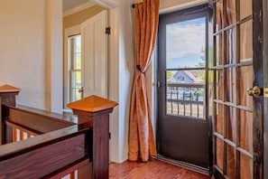 A wooden bench, a door with a view of a house, and a window with curtains.