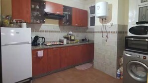 A kitchen with a refrigerator, stove, microwave, and washing machine.