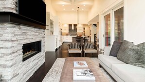 Una sala de estar moderna con una chimenea de piedra, un sofá y una mesa de centro con libros.