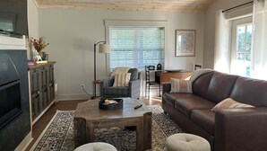 Un salon avec un plafond en bois, un canapé en cuir marron, une table basse et un tapis à motifs.