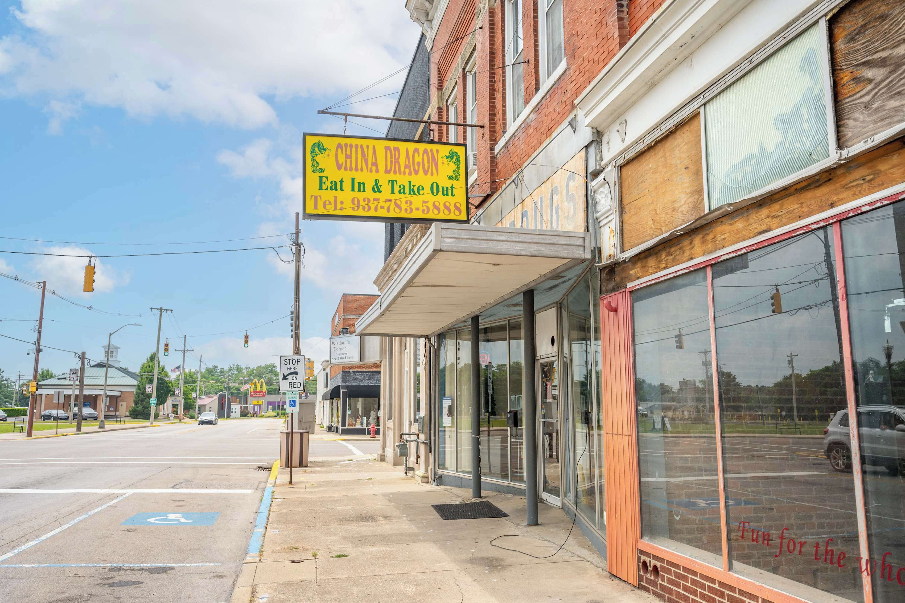 A street view with a yellow sign for a restaurant named 'China Dragon' and a storefront with large windows.