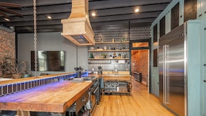 Una cocina moderna con encimera de madera, electrodomésticos de acero inoxidable y pared de ladrillo.